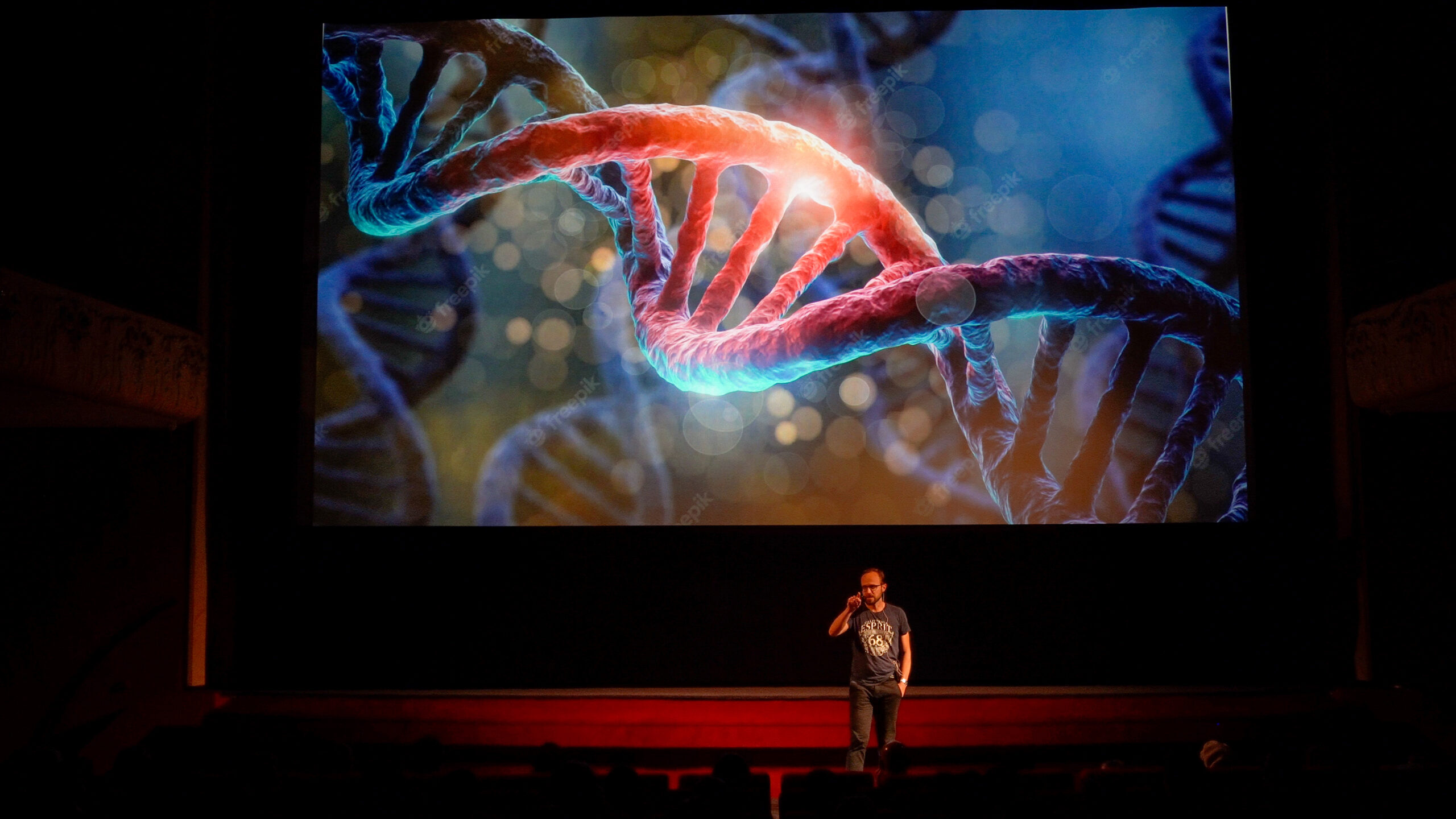 Person standing in front of big screen showing a strain of DNA.